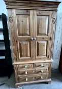 A 20th century pine wardrobe / chest with a moulded dentil cornice above a pair of cupboard doors,