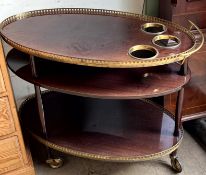 A drinks trolley of oval form with a gilt gallery and bottle wells