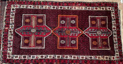 An Afghan rug, with a red ground and three medallions and multiple guard stripes,