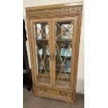 A 20th century display cabinet with a moulded cornice with glass doors and sides with a base drawer