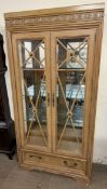 A 20th century display cabinet with a moulded cornice with glass doors and sides with a base drawer