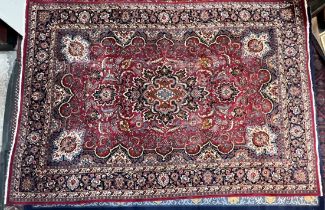 A large red ground rug, with a large central medallion scrolling leaves and flowers,