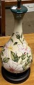 A Moorcroft pottery table lamp decorated with flowers and leaved to a cream ground
