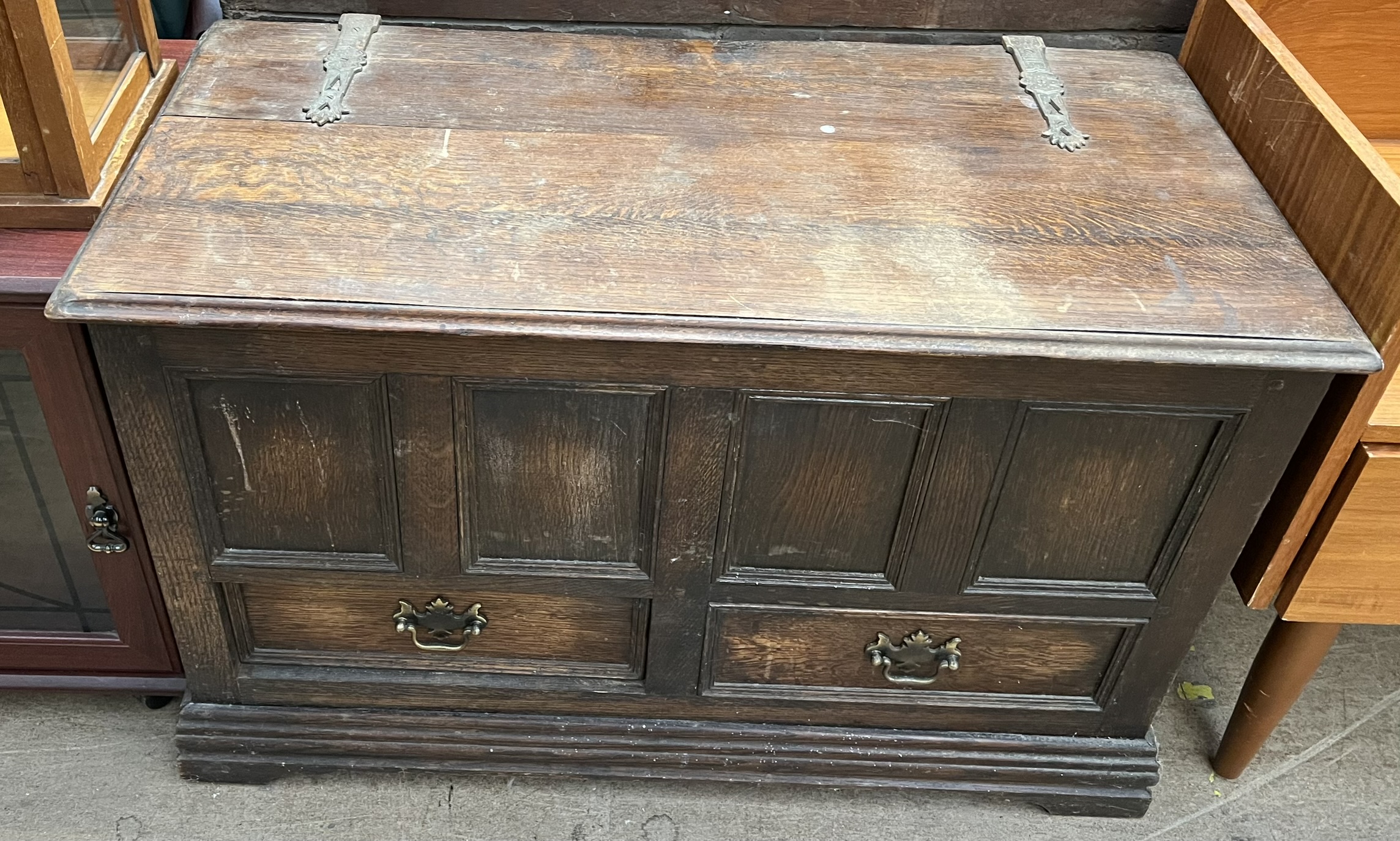 A 20th century oak coffer with a planked top and panelled front with drawers on bracket feet