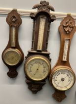 An oak aneroid barometer with a carved top,