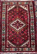 A red ground rug, the central medallion with a cream background,