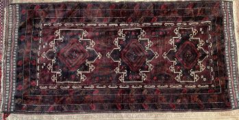 An Afghan Kafrali rug with a deep red ground and three cream highlighted medallions to multiple