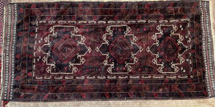 An Afghan Kafrali rug with a deep red ground and three cream highlighted medallions to multiple