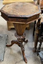 A Victorian walnut work table with a carved octagonal top above a tapering body and three carved