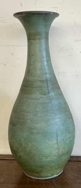 A large pottery baluster vase with a green glaze and brown interior