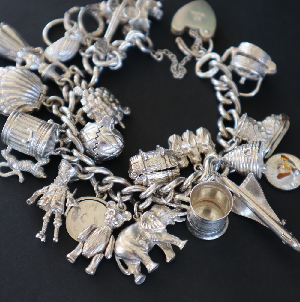 A white metal charm bracelet set with numerous charms including, a guitar, a car, a swan, shell, - Image 2 of 5