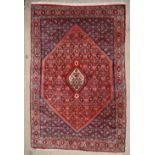 A red ground Bijar rug, with central diamond shaped medallions with multiple guards stripes,