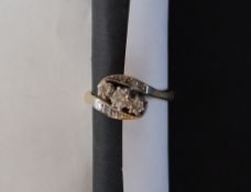 A three stone diamond ring set with round old cut diamonds to a white metal setting and yellow