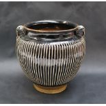 A twin handled vase in the style of a Tz'u-chou jar with white slip ribs and a dark brown glaze,