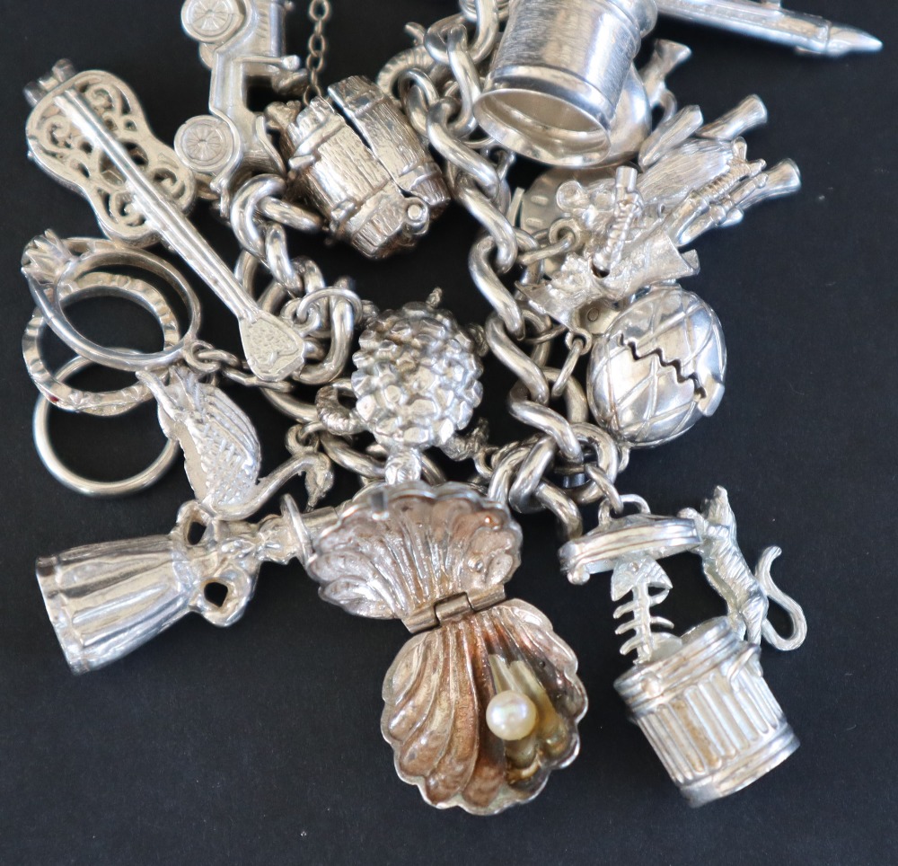 A white metal charm bracelet set with numerous charms including, a guitar, a car, a swan, shell, - Image 3 of 5