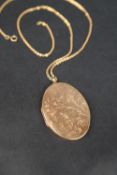 A 9ct gold locket of oval form engraved with leaves on a 9ct gold chain,