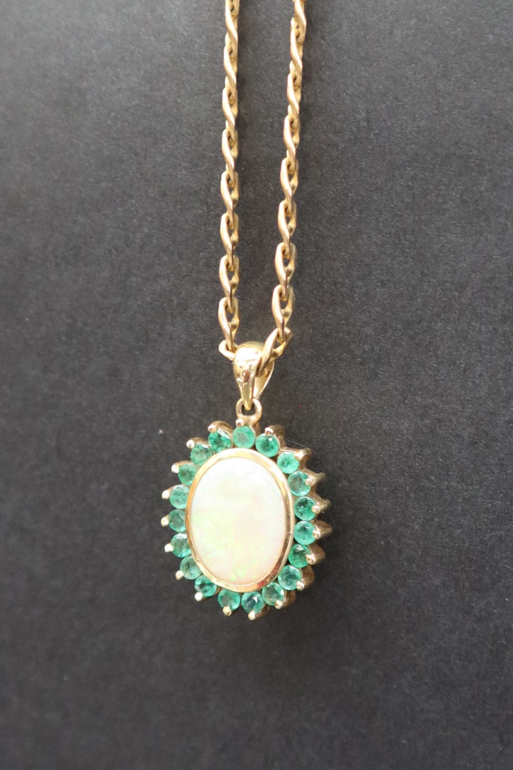 An emerald and opal pendant of oval form set with a central opal and nineteen emeralds to yellow - Image 2 of 9