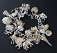 A white metal charm bracelet set with numerous charms including, a guitar, a car, a swan, shell,