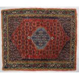 A red ground rug with a central blue medallion, and blue spandrels to multiple guard stripes,