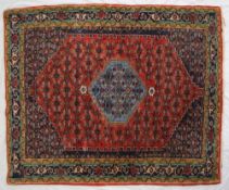 A red ground rug with a central blue medallion, and blue spandrels to multiple guard stripes,