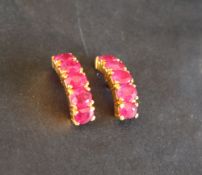 A pair of ruby hoop earrings to a yellow metal setting and post,