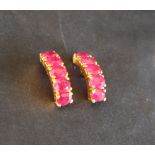 A pair of ruby hoop earrings to a yellow metal setting and post,