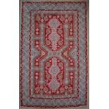 A red ground rug, with pale blue lines and flower heads, to multiple guard stripes,