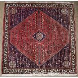 A red ground square rug, with a central medallion with individual geometric symbols,