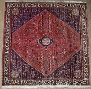 A red ground square rug, with a central medallion with individual geometric symbols,