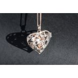 A Clogau silver hinged heart shaped pendant with suspended yellow metal angel on a white metal