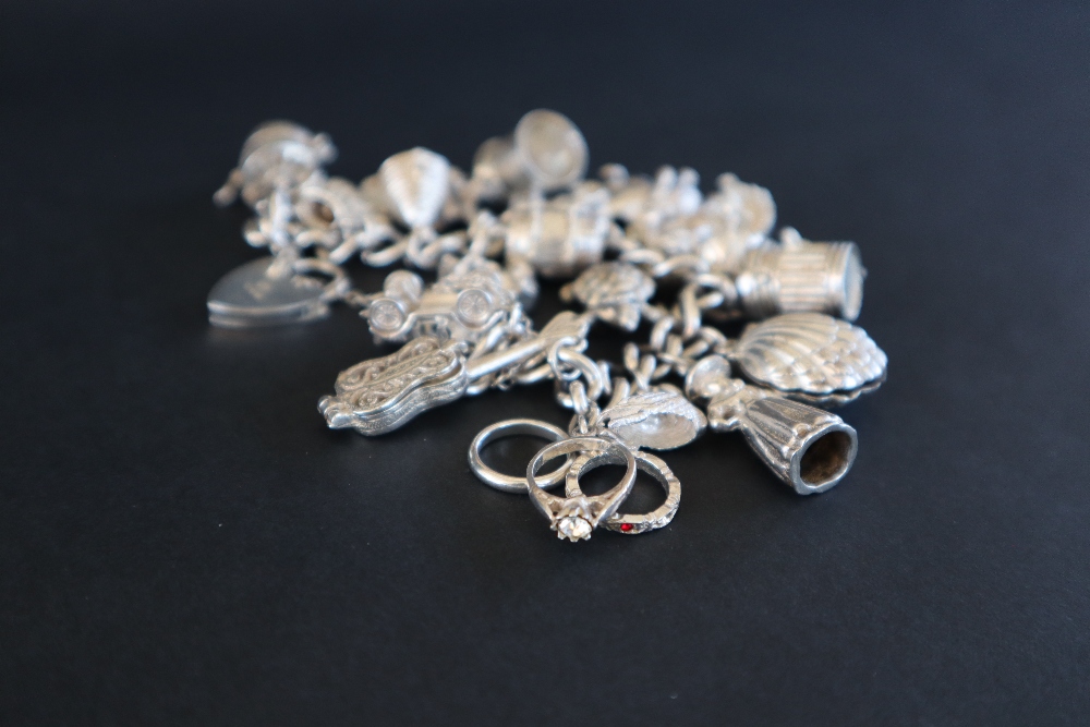 A white metal charm bracelet set with numerous charms including, a guitar, a car, a swan, shell, - Image 5 of 5