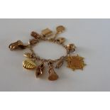 A 9ct gold charm bracelet set with numerous charms, including as kettle, medallion, lighthouse,