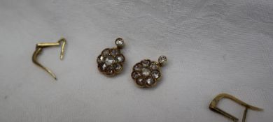 A pair of diamond drop earrings set with a single and then cluster of rose cut diamonds to a yellow