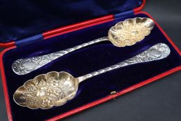 A pair of late Victorian silver berry spoons, the gilt bowls embossed with flowers and leaves,