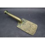 A bronze flat iron tool with a rectangular body decorated with figural heads on an integral handle,