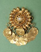 An Eastern yellow metal pearl set pendant / brooch of circular form with disc droppers,