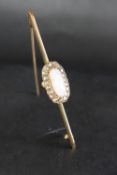 An opal and diamond bar brooch set with an oval high domed opal, 12mm long,