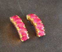 A pair of ruby hoop earrings to a yellow metal setting and post,