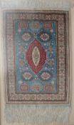 A silk rug with a blue ground and medallions to multiple guard stripes and fringes,