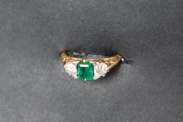 An emerald and diamond rind set with an emerald cut emerald approximately 6mm x 5mm flanked by a