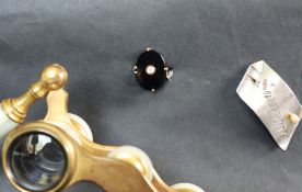 A dress ring set with a central oval onyx panel to a white metal setting and shank, size P,