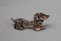 A bar brooch in the form of a dachshund, set with irregular cut diamonds, to a white metal setting,
