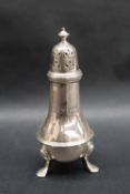 A George V silver pepperette of baluster ring turned form with a turned domed pierced finial on