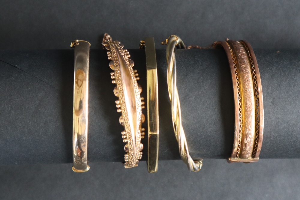 A 9ct gold hinged bangle with bead and scrolling leaf decoration together with four other hinged