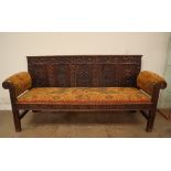 An 18th century and later carved oak settle with a carved rail and four carved panels to the back