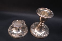An Edward VII silver desk inkwell and matching candlestick, with raised scrolling decoration,