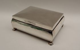 A George V silver cigarette box of rectangular form, on four flattened bun feet, Birmingham, 1912,