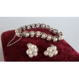 A Mikimoto pearl and white metal bracelet set with twenty regular pearls to an oval link setting