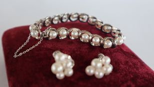 A Mikimoto pearl and white metal bracelet set with twenty regular pearls to an oval link setting