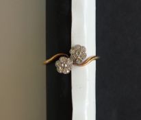 A diamond ring set with two floral settings of seven old cut diamonds,